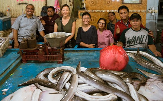 Sekelompok orang berdiri di seberang meja dengan ikan.